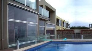Clear PVC cafe blinds installed on a modern poolside patio enclosure in Melbourne