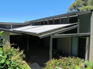 Light grey motorised retractable fabric pergola canopy extended over a modern residential patio.