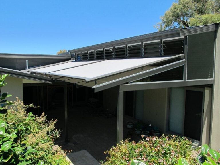 Light grey motorised retractable fabric pergola canopy extended over a modern residential patio.