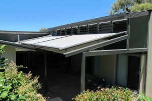Light grey motorised retractable fabric pergola canopy extended over a modern residential patio.