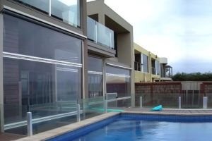 Clear PVC cafe blinds installed on a modern poolside patio enclosure in Melbourne