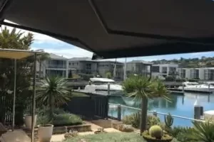 Dark grey retractable folding arm awning installed on a waterfront patio in Melbourne Australia overlooking a boat marina